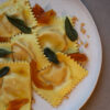 Hausgemachte Ravioli mit cremiger Kürbis-Taleggio-Füllung, Nussbutter, Salbei, gepickeltem Kürbis und Amarettini. Ein herbstliches Pasta-Rezept mit besonderem Twist.