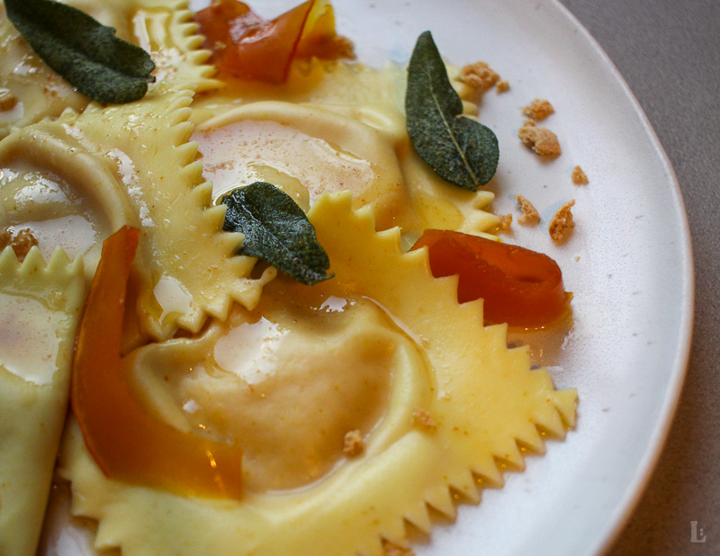 Hausgemachte Ravioli mit cremiger Kürbis-Taleggio-Füllung, Nussbutter, Salbei, gepickeltem Kürbis und Amarettini. Ein herbstliches Pasta-Rezept mit besonderem Twist.