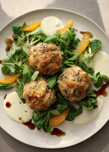 Fluffige Brezenknödel mit Kürbiskernen, serviert auf frischem Feldsalat mit Orangenfilets und Zitronen-Crème fraîche.