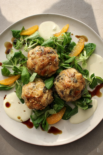 Fluffige Brezenknödel mit Kürbiskernen, serviert auf frischem Feldsalat mit Orangenfilets und Zitronen-Crème fraîche.